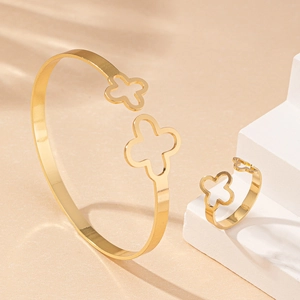Parure bijoux dorée avec trèfle évidé, comprenant bracelet réglable et bague élégante