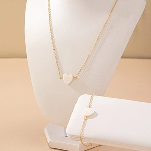 Elegant gold chain jewelry set featuring a heart-shaped shell pendant necklace and bracelet