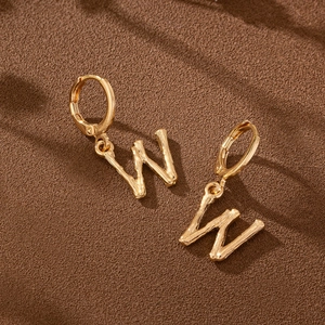 Golden bamboo texture letter W hoop earrings with minimalist aesthetic on brown background