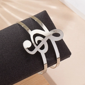 Bracelet jonc ouvert argenté avec motif de clé de sol sur présentoir en velours noir