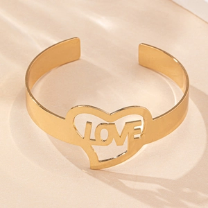Dettaglio di un bracciale dorato con design a cuore traforato e scritta LOVE al centro