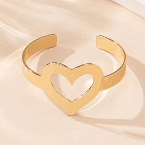 Détail d'un bracelet jonc ouvert doré avec cœur évidé et finition polie brillante