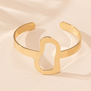 Macro shot of irregular hollow cutouts on a polished gold open cuff bracelet