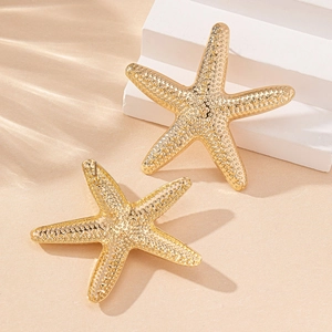 Golden starfish stud earrings with realistic textured surface on white display stone