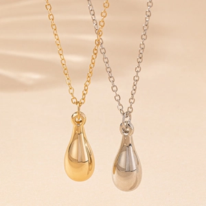Detailed view of polished gold and silver teardrop pendants on delicate link chains