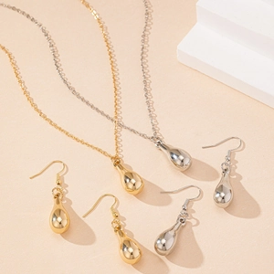 Macro detail of tear-drop necklace and hook earrings in polished gold and silver finishes