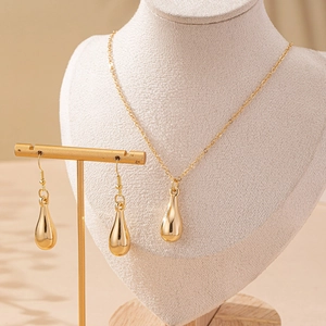 Elegant gold teardrop jewelry set featuring a necklace and drop earrings on white display