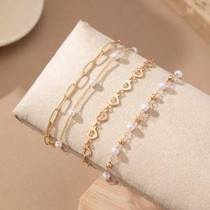Elegant 4pcs set of gold hollow heart and pearl bracelets displayed on a jewelry stand