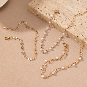 Three-piece gold-tone bracelet set with hollow heart motifs and elegant faux pearls