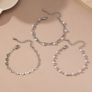 Detailed view of silver heart hollow bracelets and white pearl jewelry set on stone base