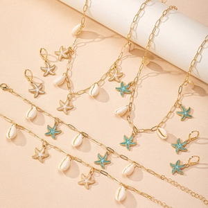 Dettaglio del set di gioielli con stelle marine e conchiglie su trama sabbiosa