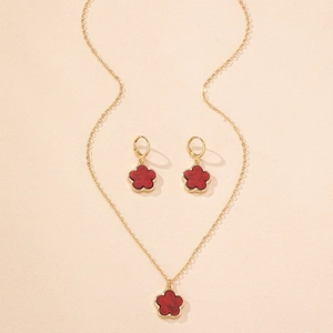 Detailed view of elegant gold necklace and earrings set with red clover pendants