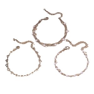 Set of three gold-tone bracelets featuring layered chains, hollow hearts, and white pearls