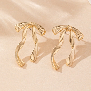 Close-up of elegant gold bow stud earrings with a flowing ribbon design on stone