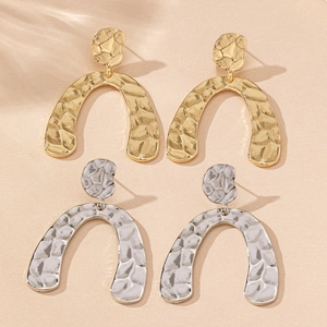 Detail shot of gold and silver irregular hammered geometric U-shaped drop earrings