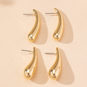 Close-up of golden teardrop stud earrings with a polished finish on textured paper