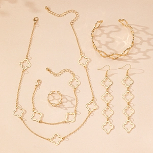 Flat lay of gold hollow clover jewelry set including necklace, bracelet, and earrings