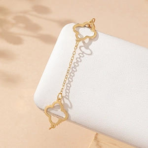 Elegant gold hollowed clover anklet with delicate chain on a soft textured background