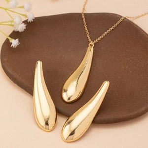 Elegantes goldenes Tropfen-Schmuckset mit Kette und Ohrringen auf Keramikteller