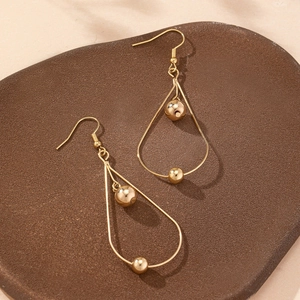 Elegant gold-tone teardrop dangle earrings with polished beads on a textured plate