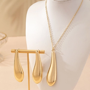 Elegantes Set aus goldener Tropfen-Halskette und Ohrringen auf einem Schmuckständer präsentiert