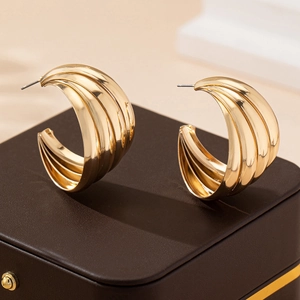 Chunky gold-plated C-shape multi-layered hoop earrings displayed on a dark jewelry box