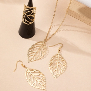 Hollow leaf jewelry set with gold necklace, earrings, and ring on warm beige background