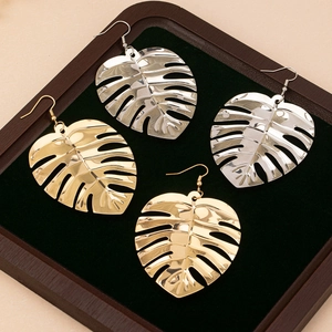 Boucles d'oreilles feuilles évidées dorées et argentées sur plateau en velours vert