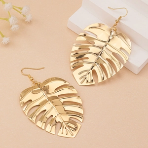 Boucles d'oreilles feuilles de monstera dorées évidées sur présentoir élégant