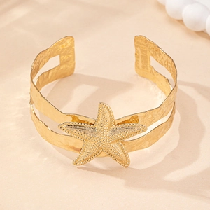 Detailed close-up of golden starfish arm cuff with textured bands for beach vacation wear
