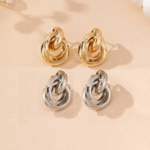 Detailed view of intertwined gold and silver round knot stud earrings in a flat lay