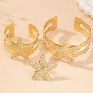 Detail showing hammered texture and starfish charms on golden bracelet and ring set