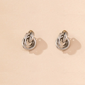 Detail of silver knot stud earrings with a hollow interlocking multi-ring design