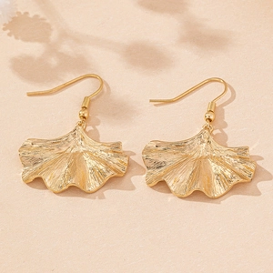 Detailed close-up of golden ginkgo leaf earrings with realistic vein textures on beige background