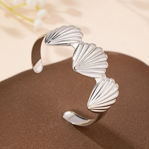 Elegant silver open shell cuff bracelet with textured fan motifs on a premium display
