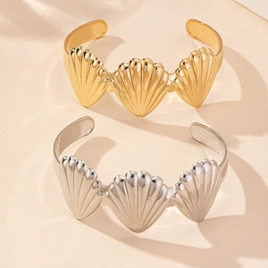 Detailed close-up of shell-shaped open cuff bracelets in polished gold and silver finishes