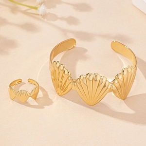 Close-up of golden shell jewelry set featuring a textured cuff bracelet and matching ring