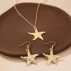 Elegant gold starfish necklace and earrings set with textured finish on warm tray