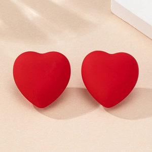 Macro di orecchini a cuore rosso opaco 3D su una superficie strutturata minimalista