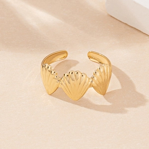 Macro detail of gold-plated shell ring with sea-inspired relief on sandy surface