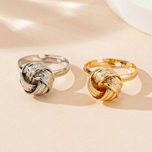 Detail of twisted knot gold and silver rings with textured finish and adjustable open band