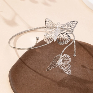 Bracelet manchette papillon argenté avec design ajouré sur plateau de présentation