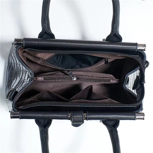 Macro view of interior compartments and brown lining of the black crocodile embossed handbag