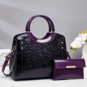 Detailed view of purple patent leather handbag set with 3D floral embossing and gold hardware