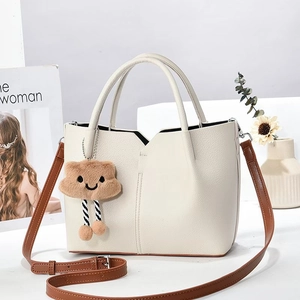 Nahaufnahme cremeweiße Handtasche aus Leder mit braunem Riemen und Plüsch-Wolkenanhänger