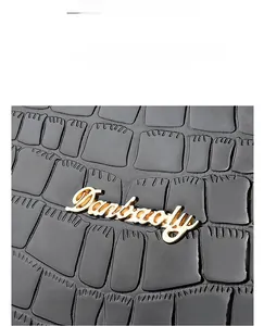 Detailed view of crocodile pattern black faux leather texture with golden brand logo
