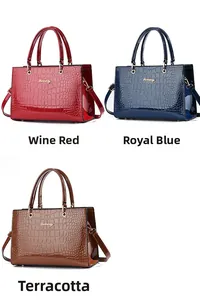 Detailed view of crocodile embossed glossy handbags in wine red, royal blue, and khaki