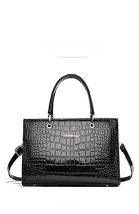 Macro detail of black crocodile embossed glossy leather with gold logo and hardware