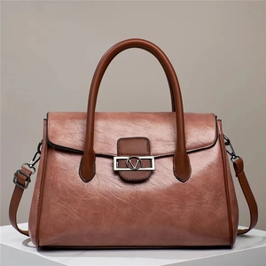 Detail view of pink tote bag with brown leather handles and decorative V-shaped metal buckle