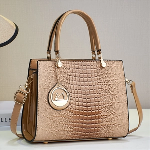 Detailed view of beige lizard pattern tote bag with swan pendant on wooden surface